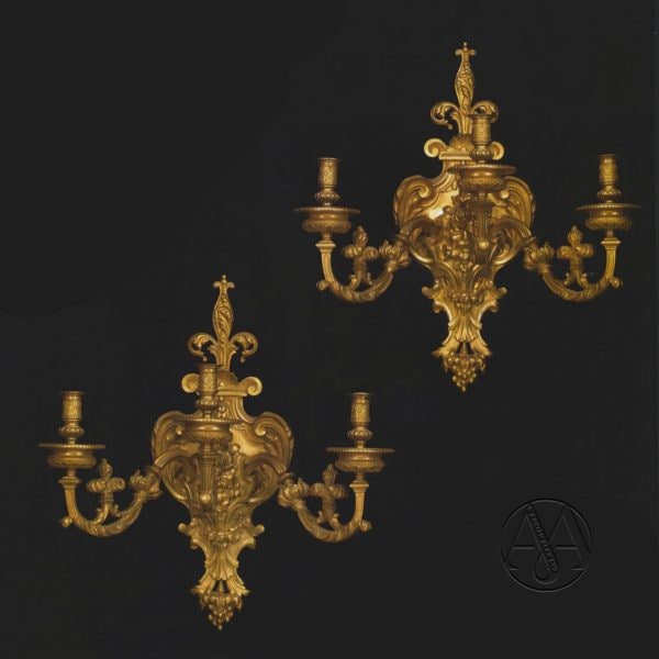 Un fino par de apliques de tres luces de bronce dorado