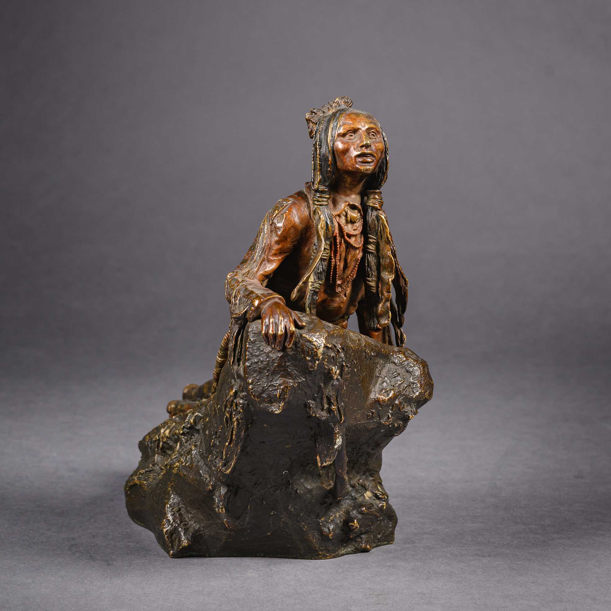 Patinated bronze figure of a Native American scout peering over a rocky outcrop by Carl Kauba, signed in the cast, Austrian circa 1910.
