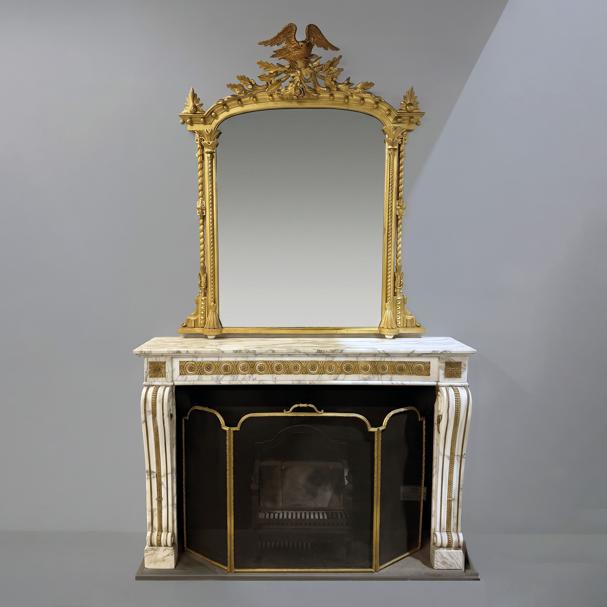 a carved antique English giltwood overmantel above a marble fireplace