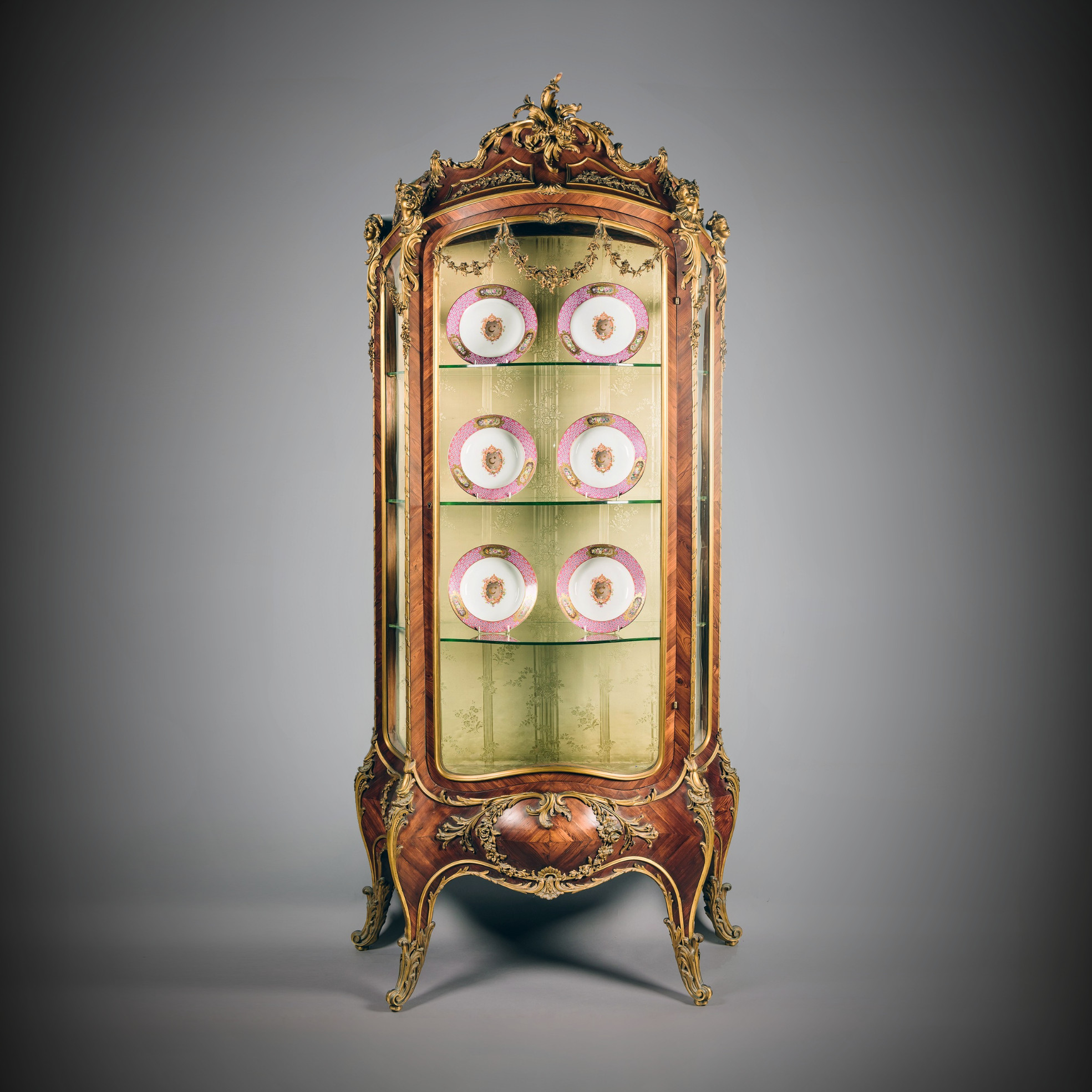 Louis XV style gilt-bronze mounted bombé vitrine attributed to Maison Krieger with glazed door, concave sides, figural espagnolettes, and floral mounts, silk-lined interior, circa 1880.