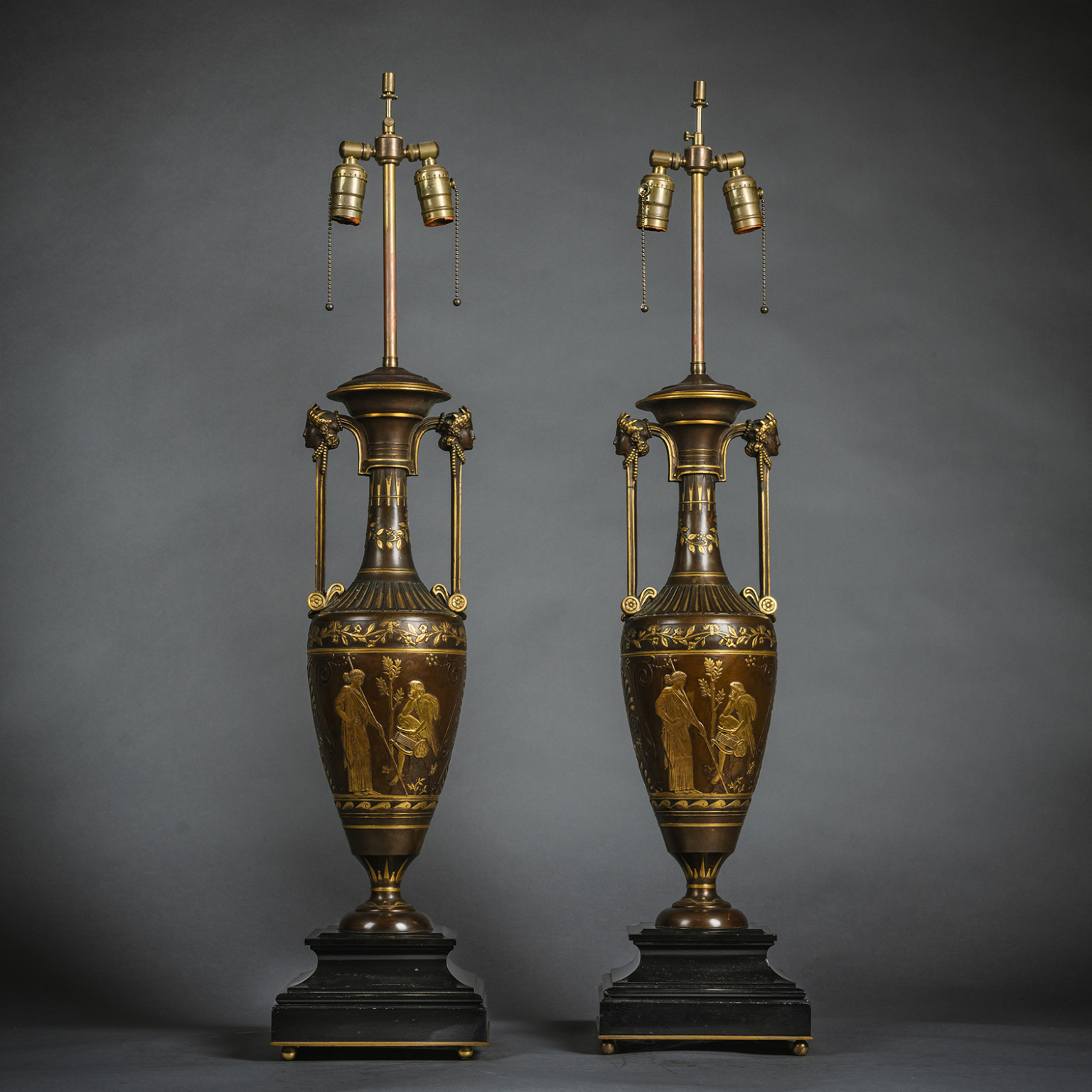 Pair of Néo-Grec parcel-gilt and patinated bronze vases by Ferdinand Barbedienne after Henry Cahieux, with herm handles and classical reliefs, mounted as lamps on black marble bases, circa 1870.