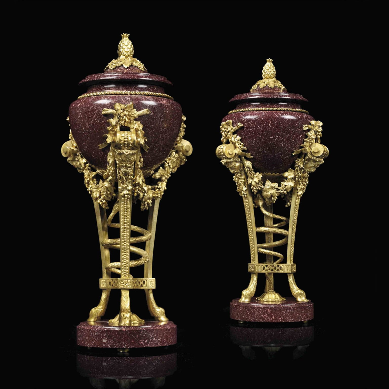 Pair of Louis XVI style gilt bronze mounted porphyry urns with satyr mask mounts and vine decoration, French circa 1870 after the model by Pierre Gouthière