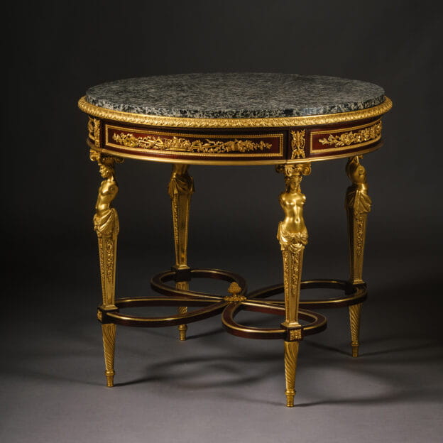 A rare Louis XVI style mahogany centre table by Henry Dasson, dated 1878, featuring finely cast gilt-bronze mounts, Granito Nero marble top, seasonal trophy frieze panels, and figural term legs joined by an interlaced stretcher.