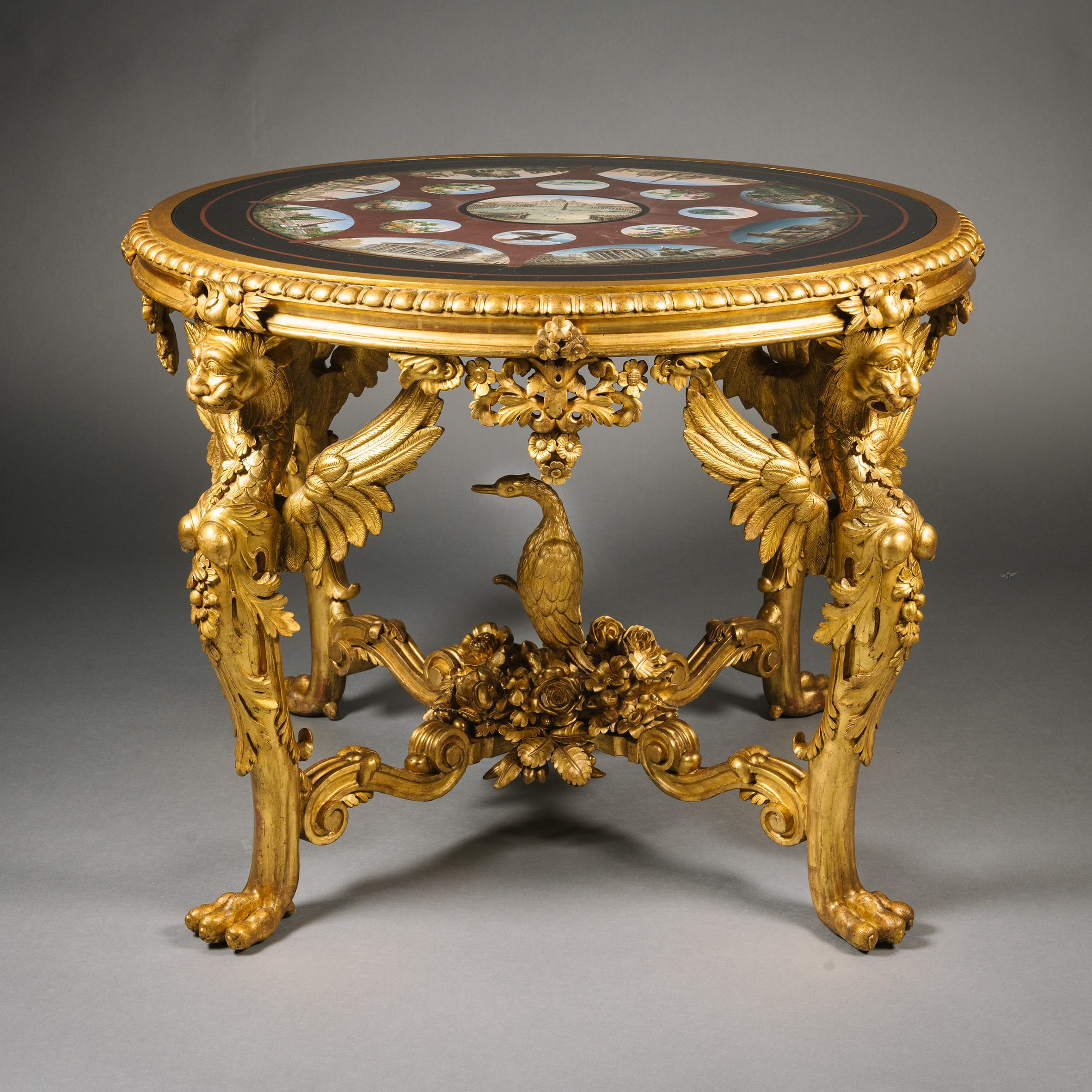An elaborately carved giltwood table with a pietre dure marble top depicting scenes of Rome's famous landmarks