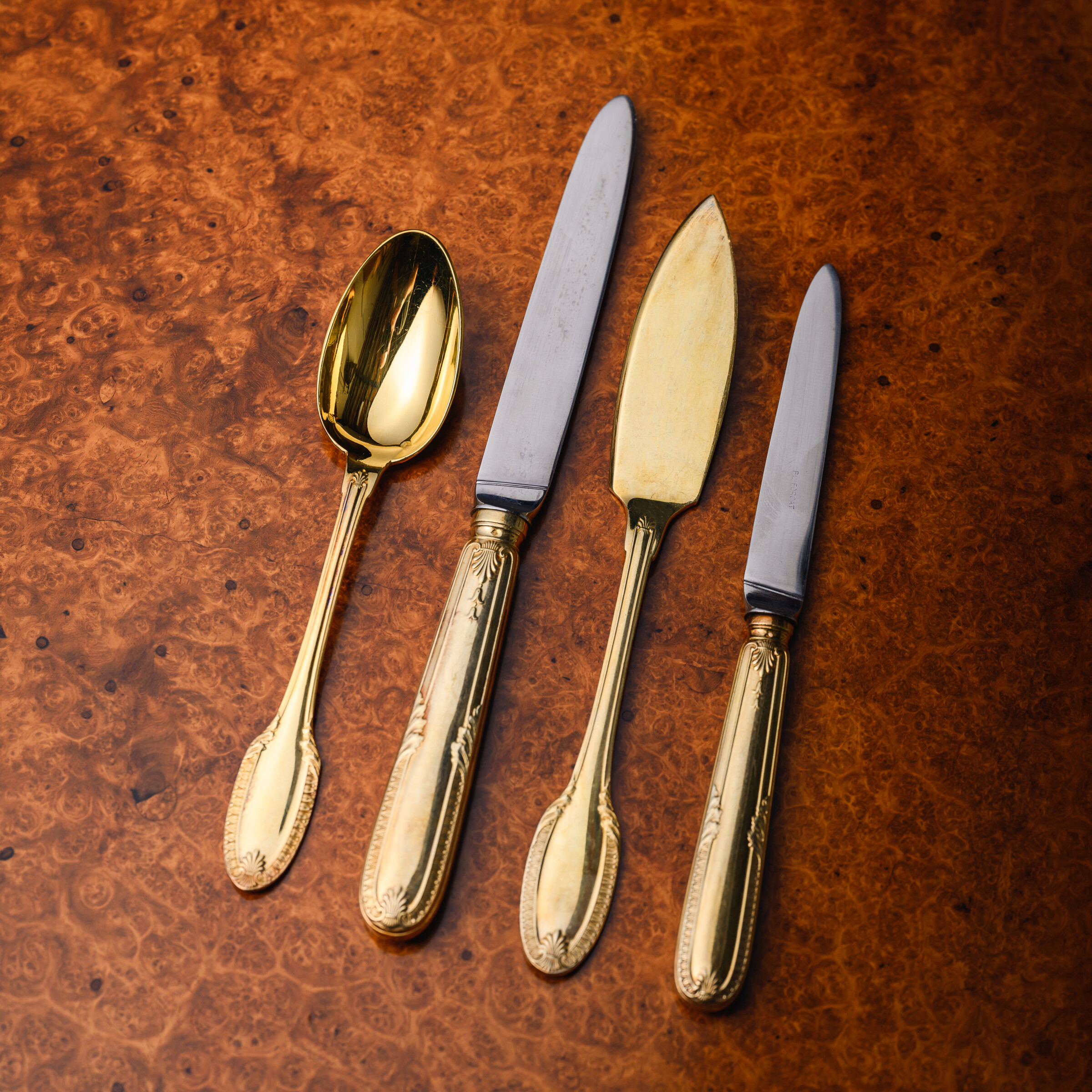 Selection of Puiforcat Percier pattern silver-gilt table knives, finely balanced with crisp neoclassical handles, shown in detail to highlight the elegant form and precision finishing