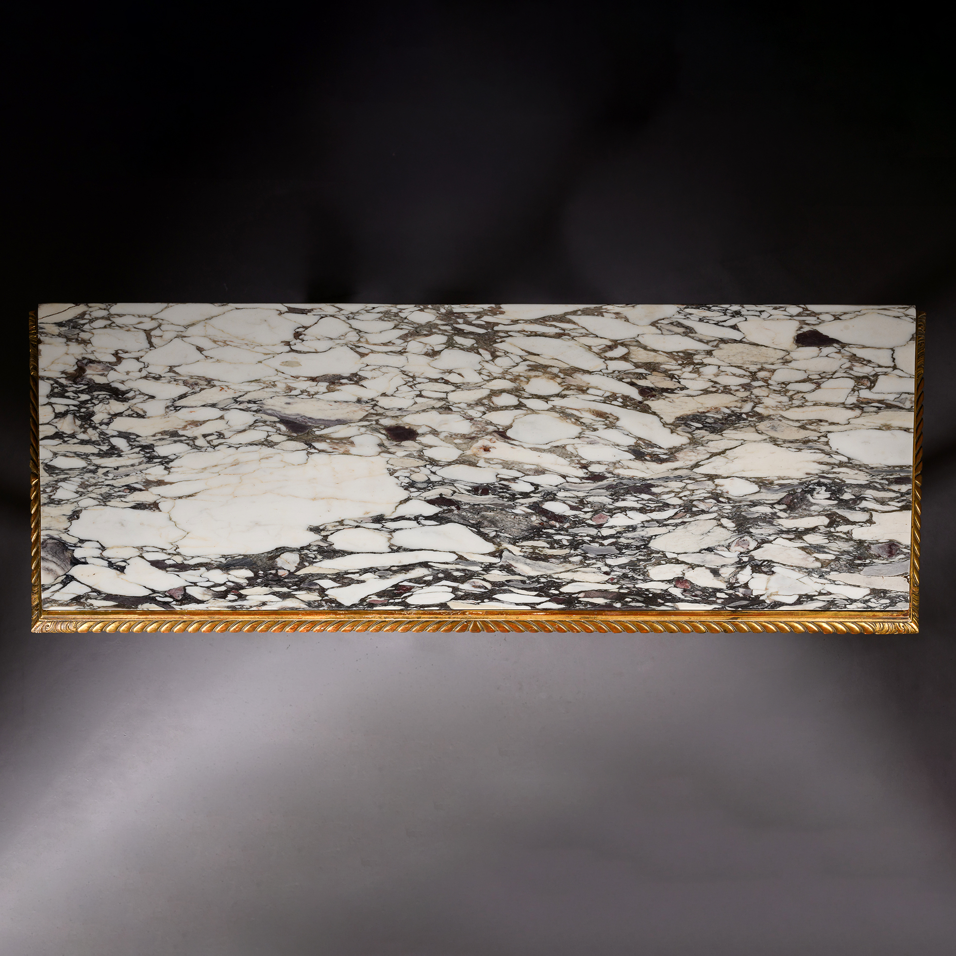 Fine gadrooned carving framing the striking brèche violette marble top.