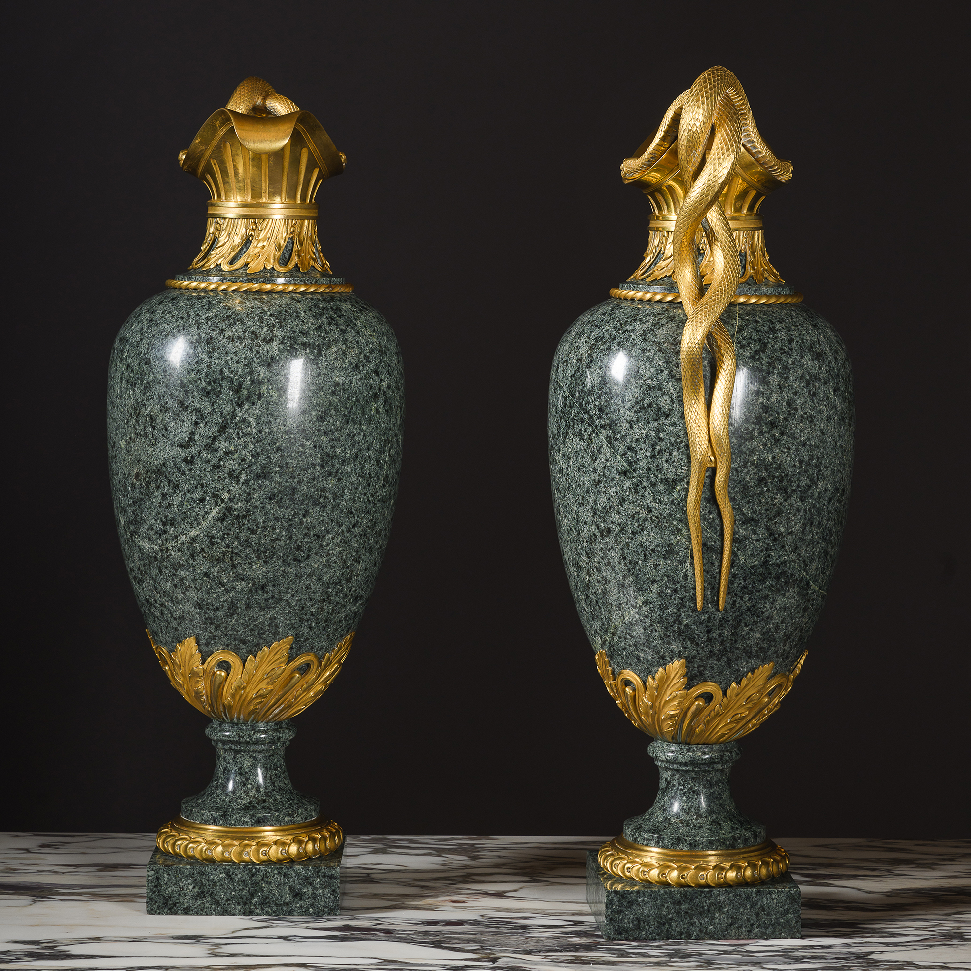 Polished green granite bodies of a pair of Louis XVI style ewers by Henry Dasson resembling antique green porphyry.