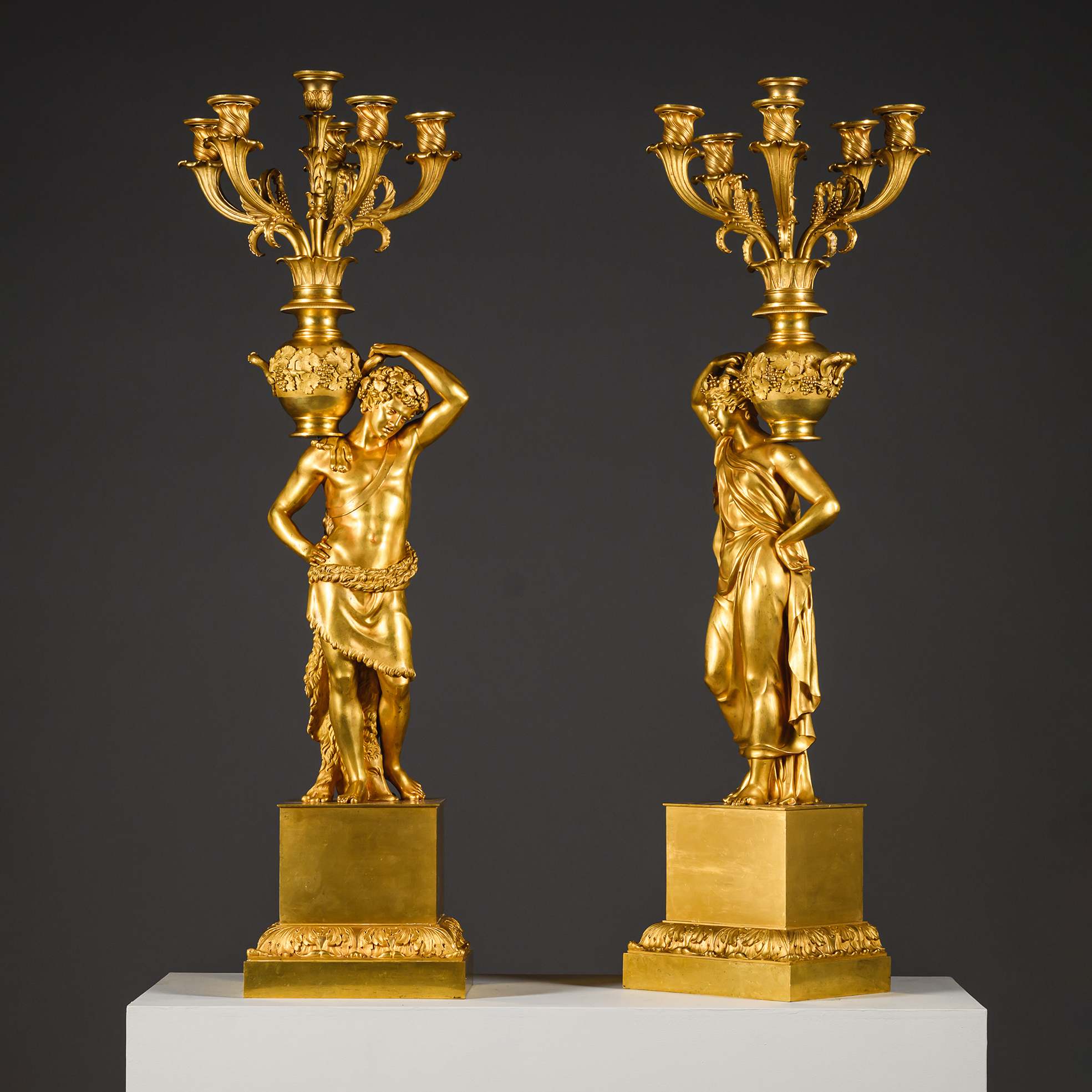 Monumental French gilt-bronze candelabra featuring classical male and female figures supporting amphora-form candle branches.
