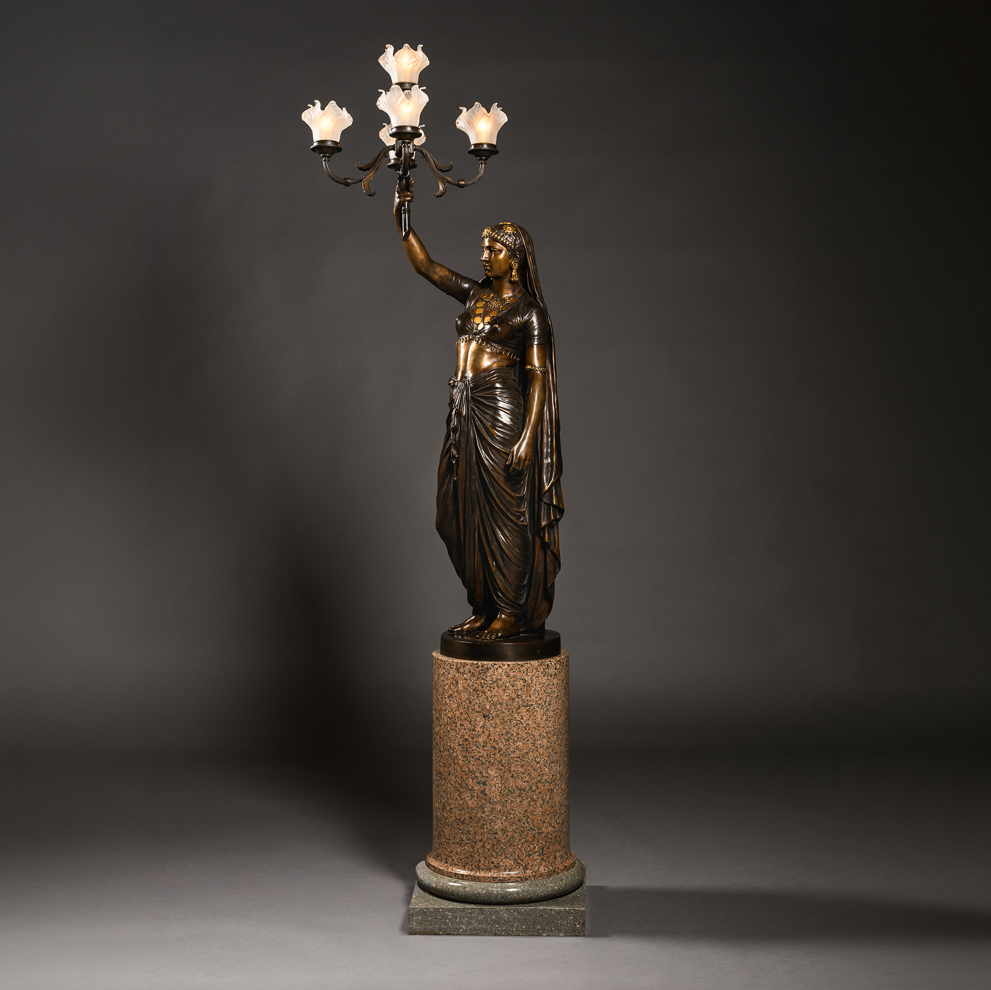 Émile Guillemin’s ‘Femme Indienne’ bronze torchère, with an ornamental candelabrum above the figure and a pink granite pedestal.