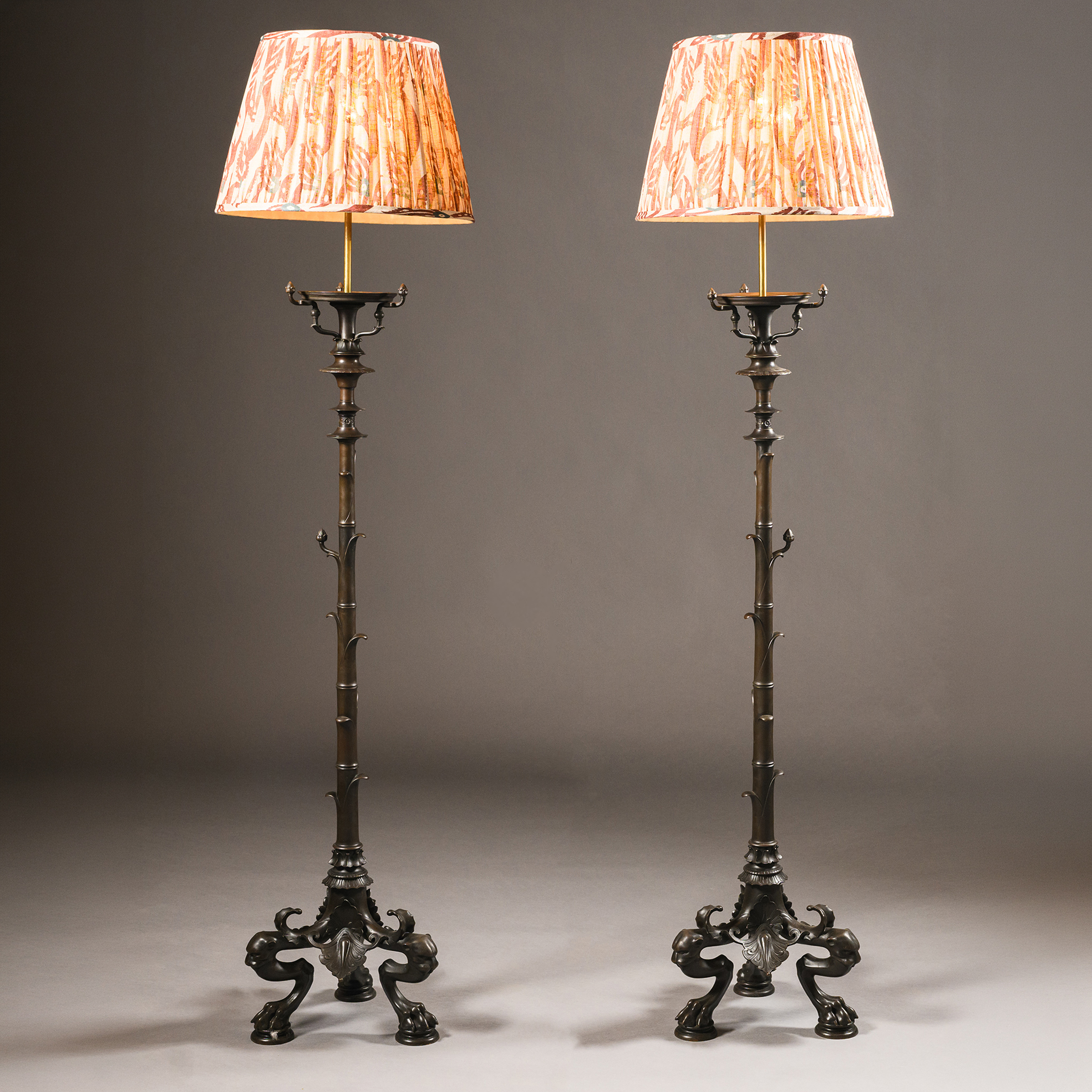 Full-length view of a pair of French neoclassical bronze standard lamps with ring-turned shafts and tripod bases supported by panther-mask monopodia.