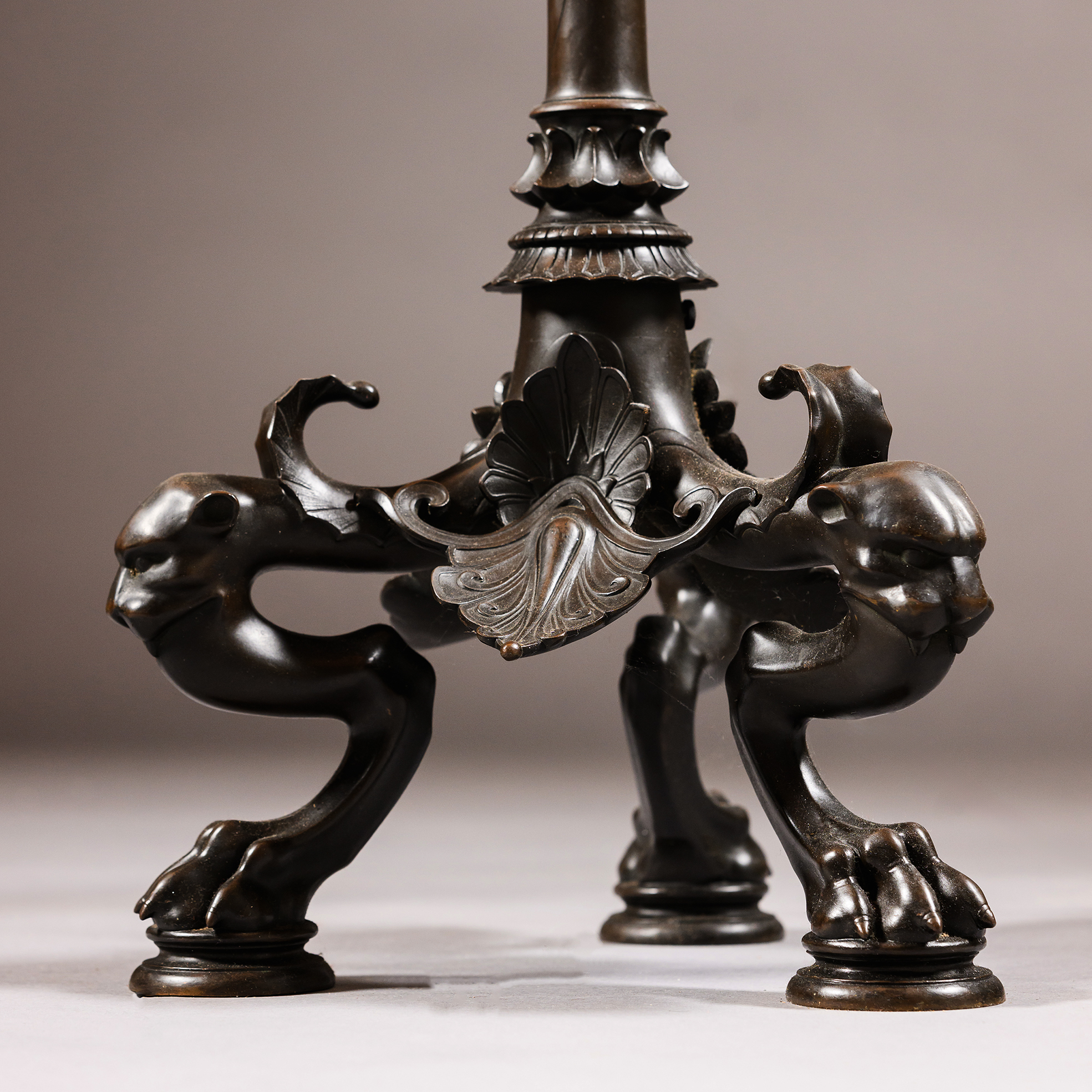 Detail of the patinated bronze tripod base, featuring three panther masks above sculptural paw feet